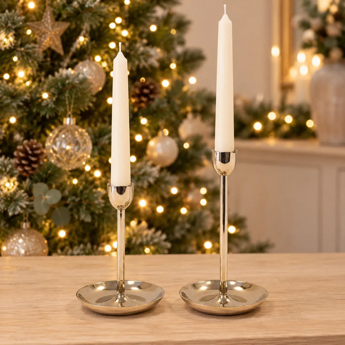 Small 16cm and large 21cm gold metal candlestick holders together with ivory candles and sparkling Christmas lights; holders sold separately
