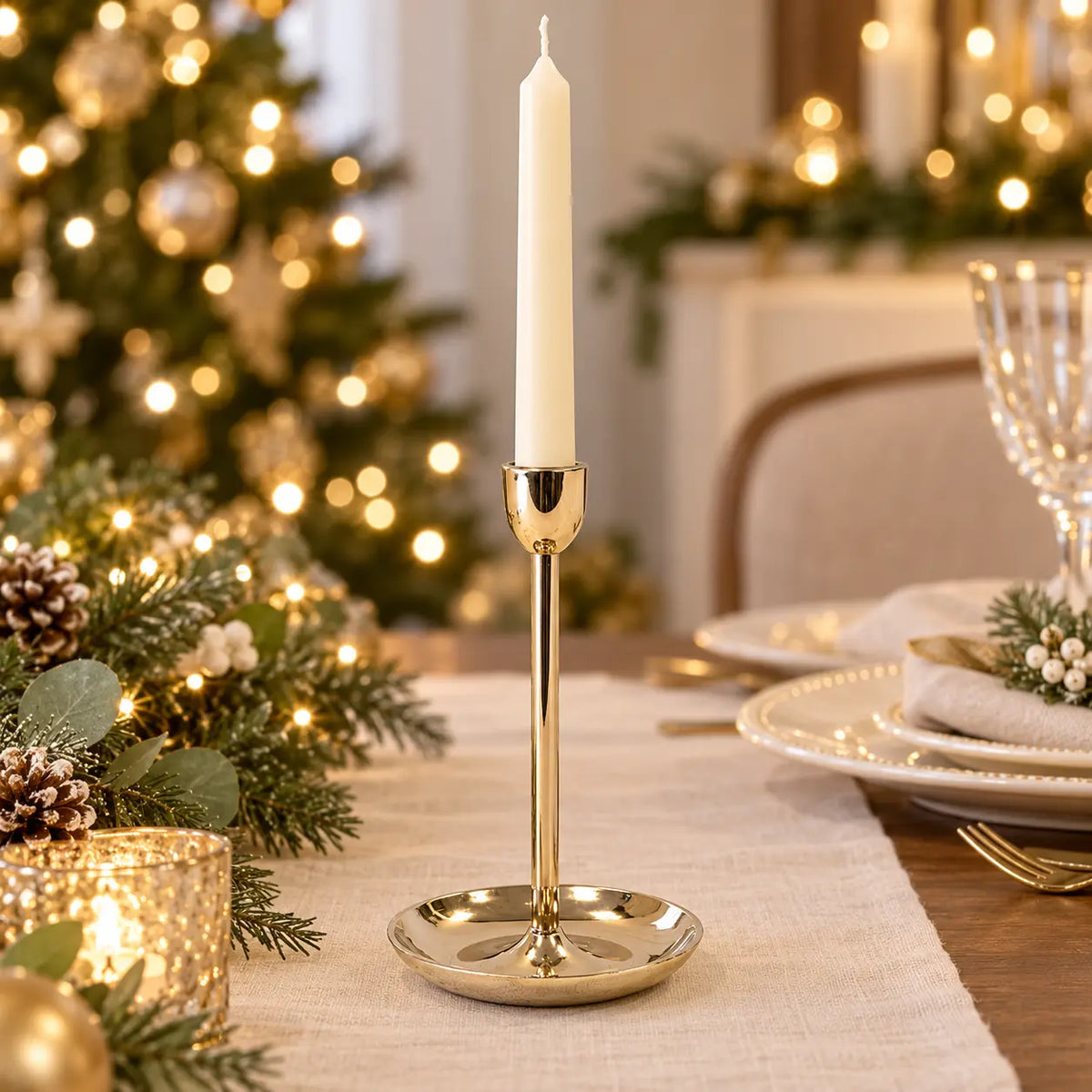 large gold metal candlestick holder with ivory candle on a Christmas dining table