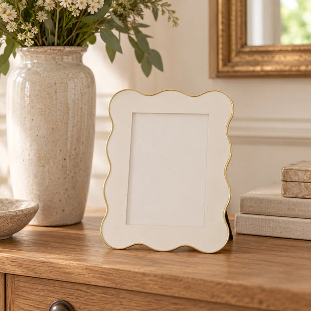 Small 4 x 6 inch ivory and gold scalloped photo frame on an oak console.