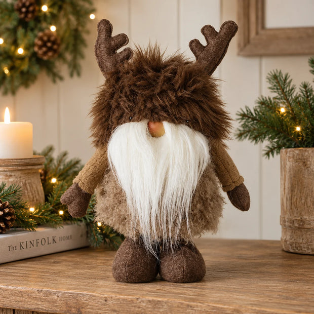 Brown antler Christmas gonk with shaggy fur hat and long white beard styled on rustic festive mantel