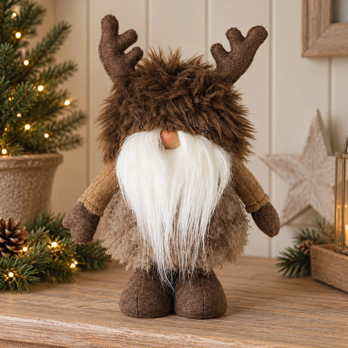 Brown furry antler gonk Christmas decoration styled beside Christmas tree and greenery