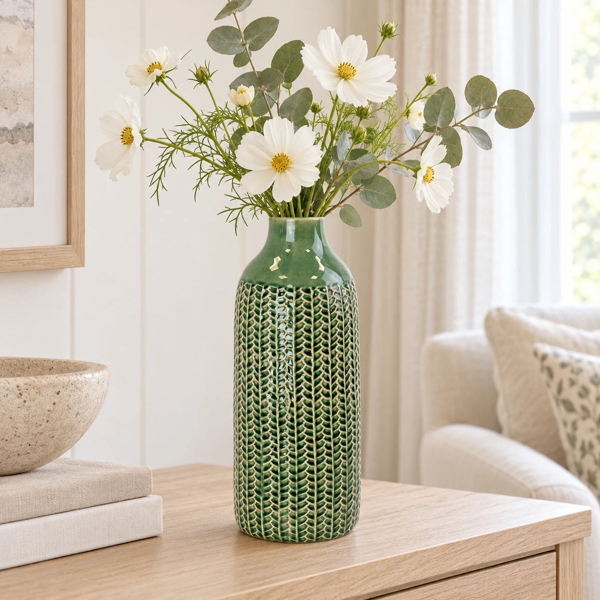 medium green ceramic vase with white flowers and eucalyptus on an oak console