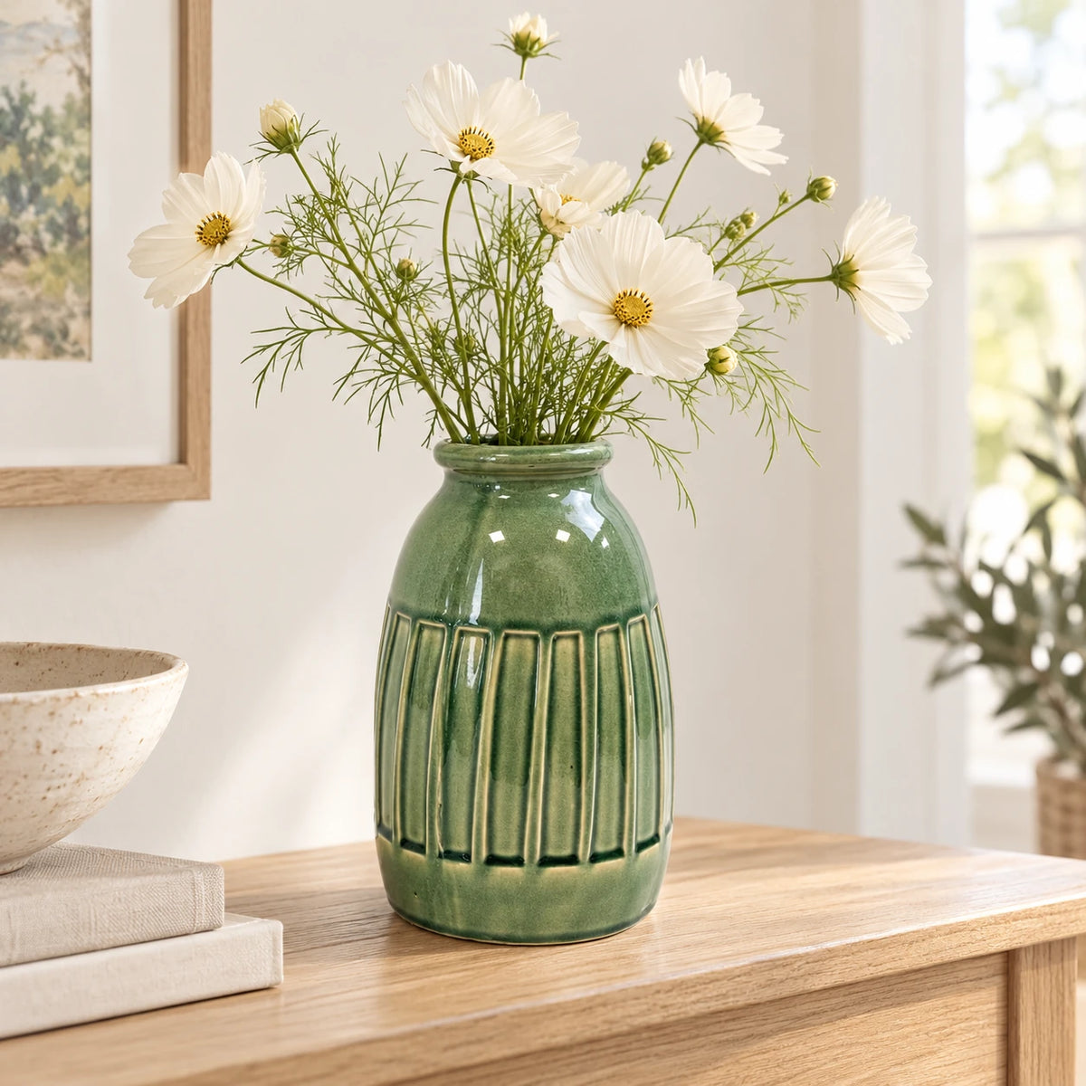 Medium green ceramic vase with airy cream cosmos stems on a light oak console in a bright everyday country home.