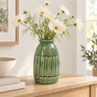 Medium green ceramic vase with airy cream cosmos stems on a light oak console in a bright everyday country home.