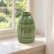 Medium green ceramic vase empty on a deep pale stone windowsill.