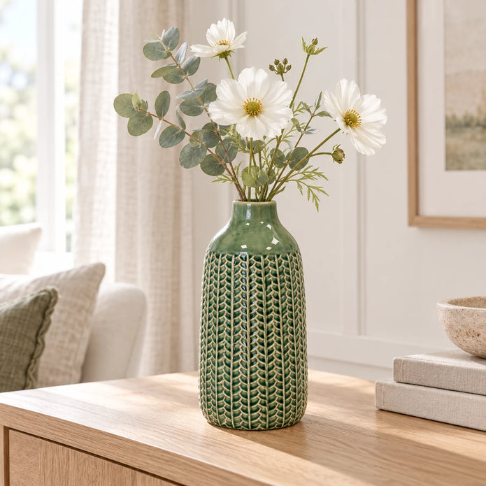 small green ceramic vase with white flowers and eucalyptus on an oak console