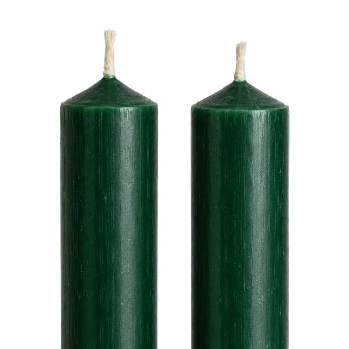 Close-up of the rustic green wax finish and unlit wicks on two dinner candles.