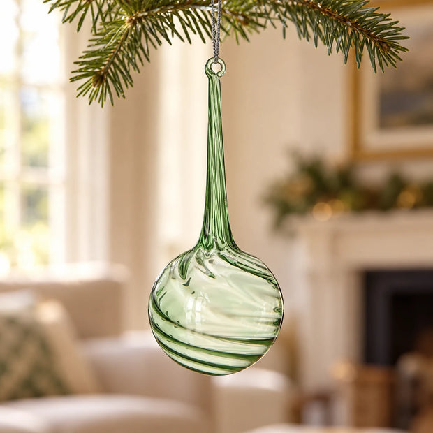 Green Glass Large Teardrop Bauble — Single bauble hanging on fir branch with cream sitting room blurred behind