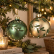 Green and gold mistletoe Christmas baubles hanging on evergreen branches with pearl berry details
