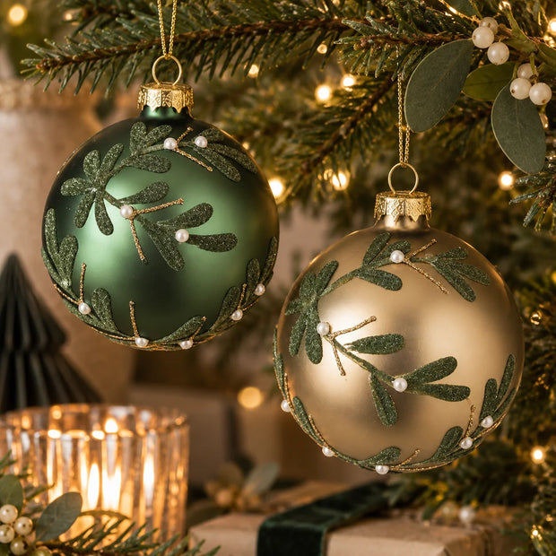 Forest green and champagne gold mistletoe baubles on Christmas tree with warm fairy lights