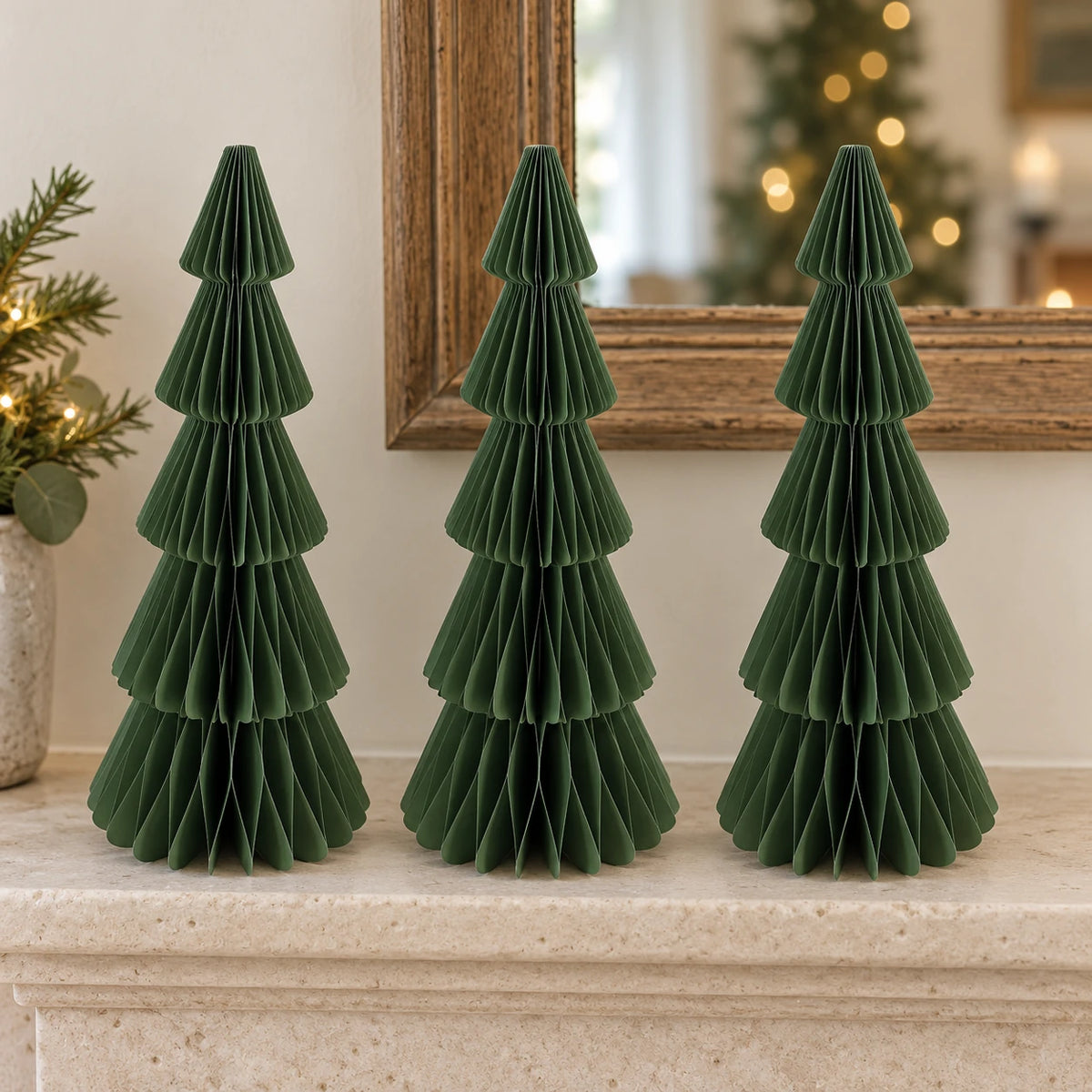 Three matching 30 cm green paper Christmas trees on a pale stone mantel.
