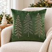 Green velvet embroidered tree cushion cover styled on a cream boucle armchair with neutral Christmas decorations.