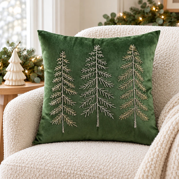 Green velvet embroidered tree cushion cover styled on a cream boucle armchair with neutral Christmas decorations.