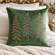 Green velvet Christmas tree cushion cover styled with ivory bedding, a cream knitted throw and festive greenery.
