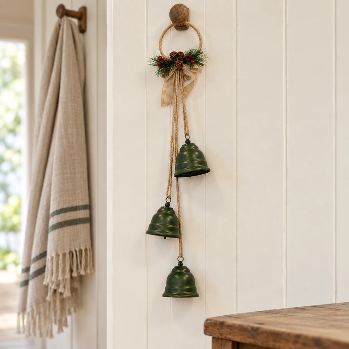 Forest green hanging bells on a jute hoop styled on an oak peg rail in a cream country hallway.