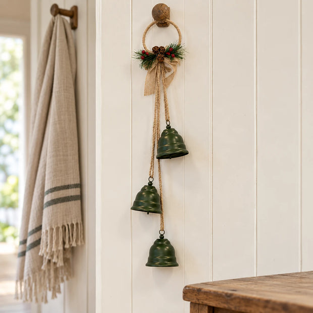 Forest green hanging bells on a jute hoop styled on an oak peg rail in a cream country hallway.