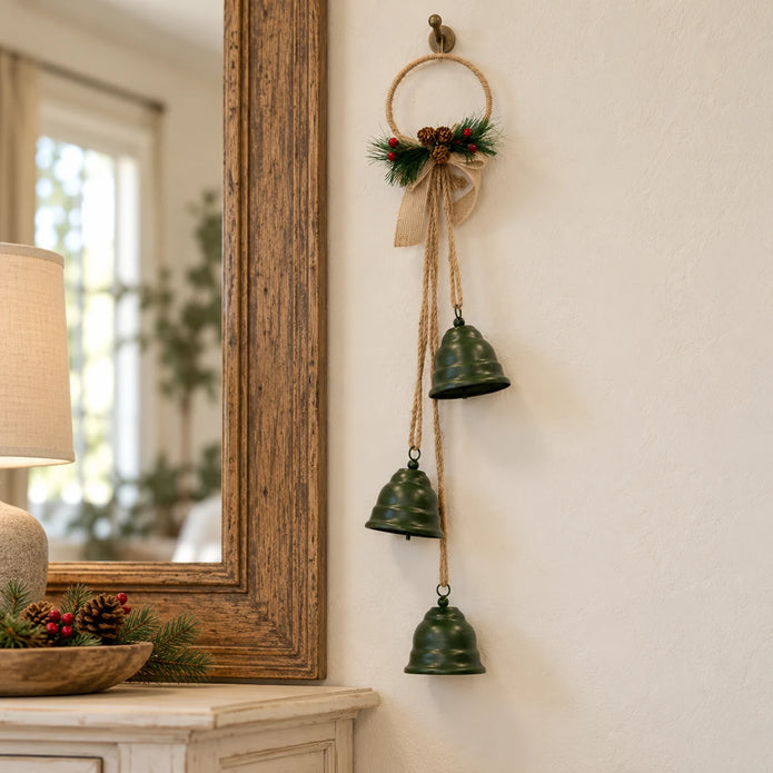 Hanging green Christmas bells with their hessian bow beside an aged oak mirror.