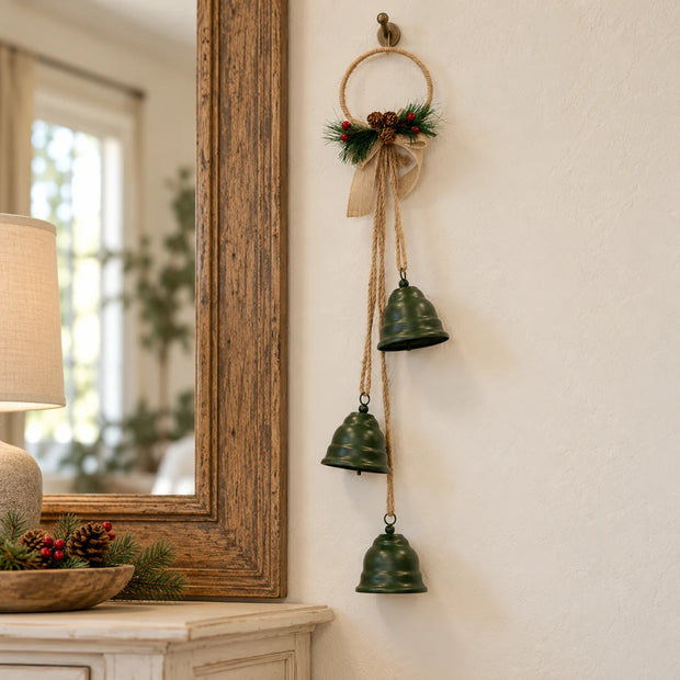 Hanging green Christmas bells with their hessian bow beside an aged oak mirror.