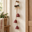 Trio of red metal bells suspended from a decorated jute hoop on a country hallway peg
