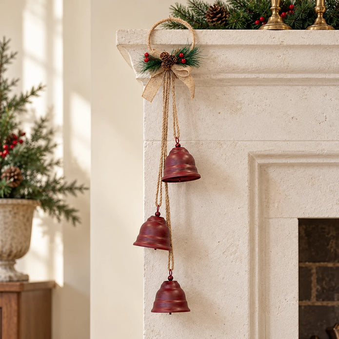 Hanging red metal Christmas bells on a jute hoop styled by a pale fireplace mantel