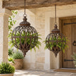Rusty metal lattice ball planters hanging in a pale stone cottage porch with ferns.