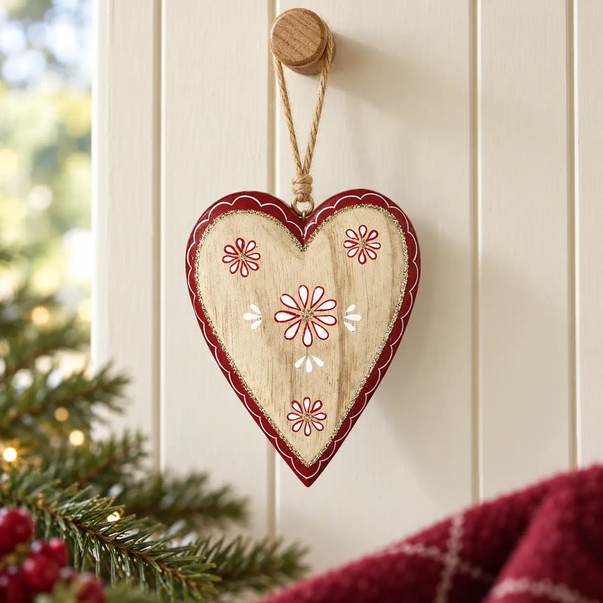 Floral wooden red heart hanging from an oak peg against cream panelling
