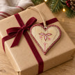 Wooden red heart with botanical pattern styled on a kraft Christmas gift