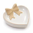 Studio detail of the unglazed beige bow and glossy white heart dish