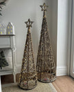 Two illuminated rattan Christmas trees with woven star toppers displayed beside a console; sold separately.