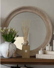 Chloe round washed wood framed mirror by Hill Interiors, hanging on a wall, showcasing its circular design and rustic wood frame.