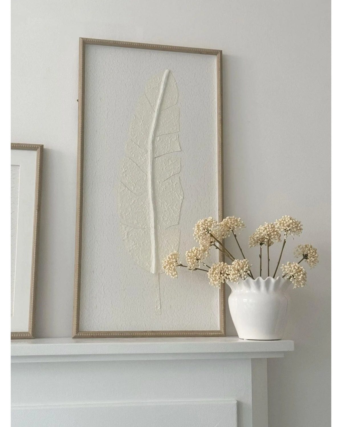 Large white feather print wall art in a frame by Hill Interiors, showcasing elegant feather design for home decor.