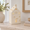 Large 17cm ivory ceramic LED house with raised flowers and gold-coloured details, mantel view, LED switched on.