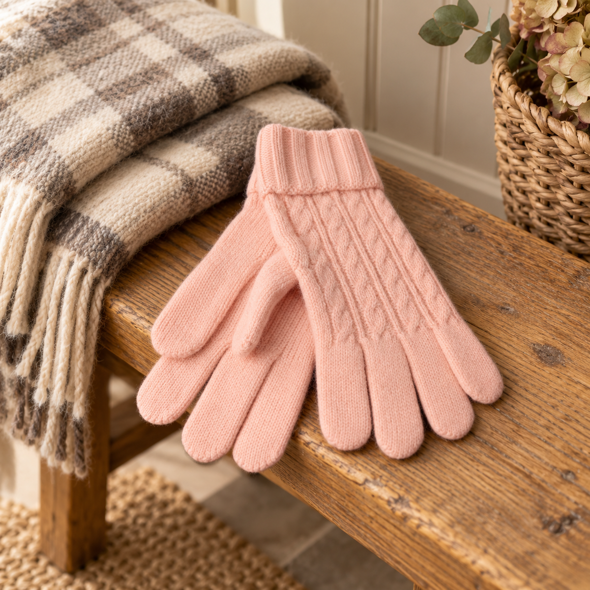 Pink cable knit gloves on a rustic wooden bench