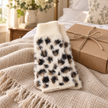 Cream leopard fluffy fingerless gloves styled beside a kraft gift box
