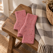 Pink speckle fingerless gloves on a rustic wooden bench