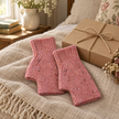 Pink speckle fingerless gloves styled beside a kraft gift box