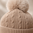 Close-up of oatmeal cable knit and matching fluffy pom-pom