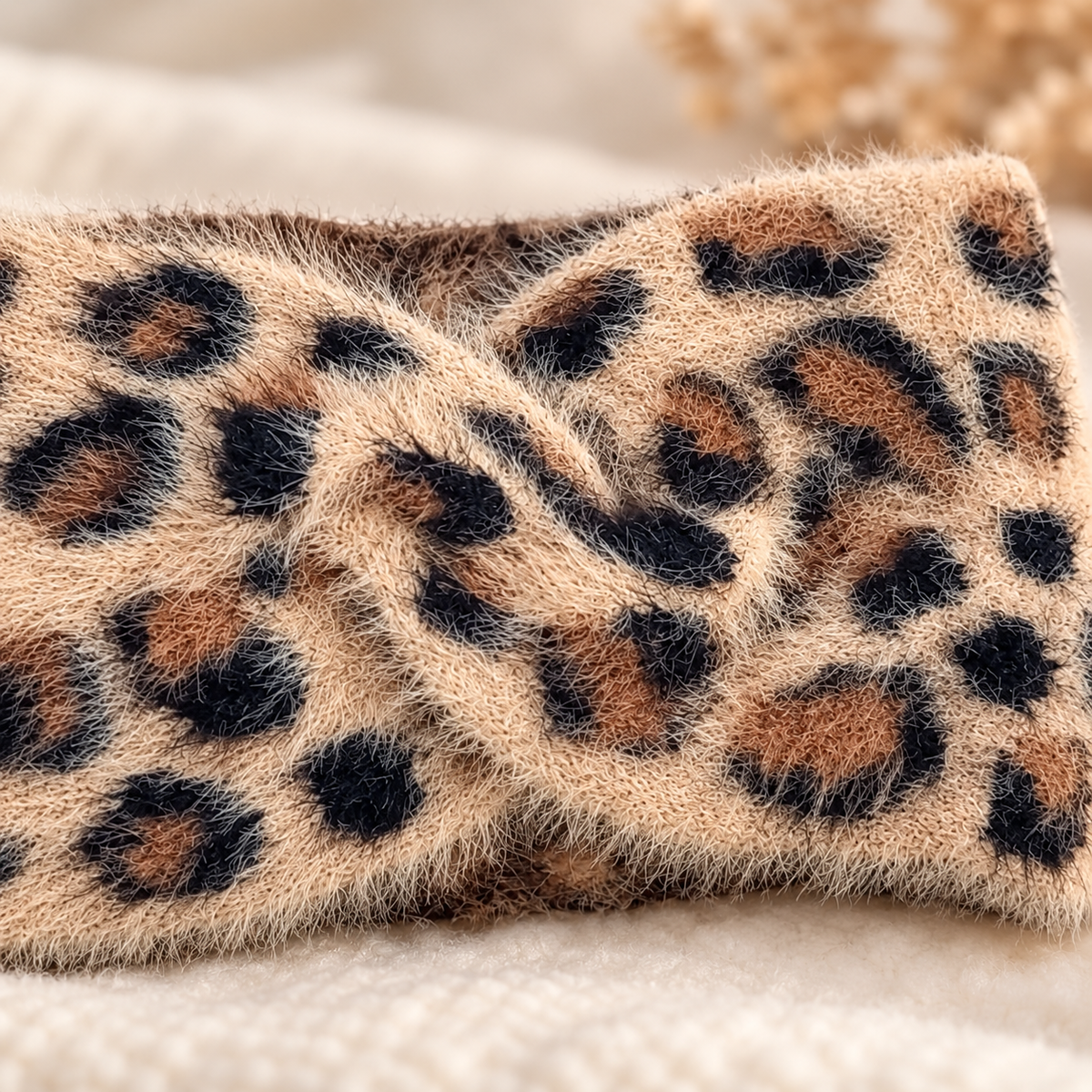 Close-up of the fluffy tan cream and black leopard headband knit