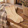 Cream and oatmeal zebra socks on a rustic wooden bench