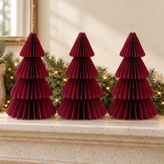 Three equal-sized burgundy paper Christmas trees side by side on a stone mantel.