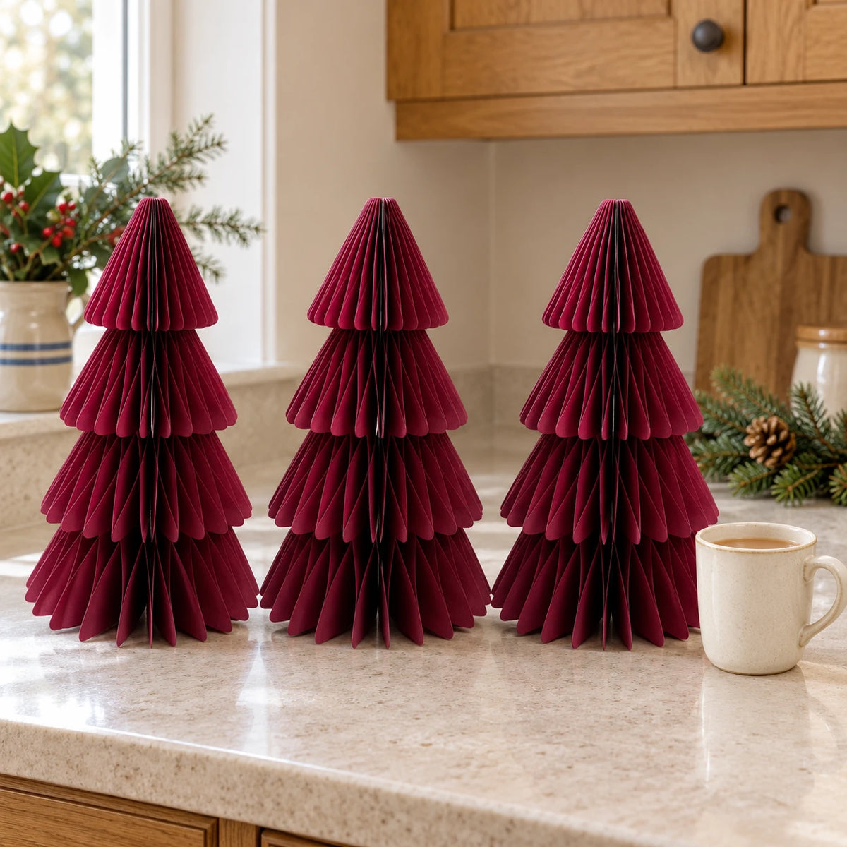 Set of three 30cm burgundy paper trees beside a mug of tea on a kitchen counter.