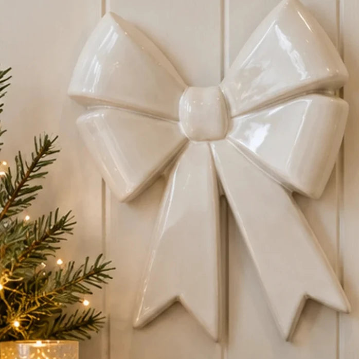 Large glossy white ceramic double bow styled on cream panelled wall above rustic console with greenery