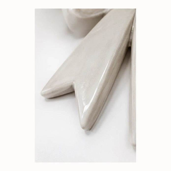 Macro detail of pointed ribbon tail on glossy white ceramic wall bow