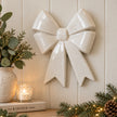 Glossy white ceramic double bow wall decoration styled above a country-home console with eucalyptus and candle