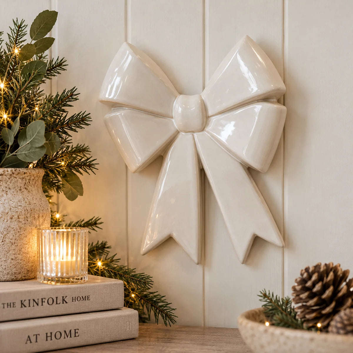 White glazed ceramic bow wall decor in an elegant neutral home with books greenery and soft candlelight