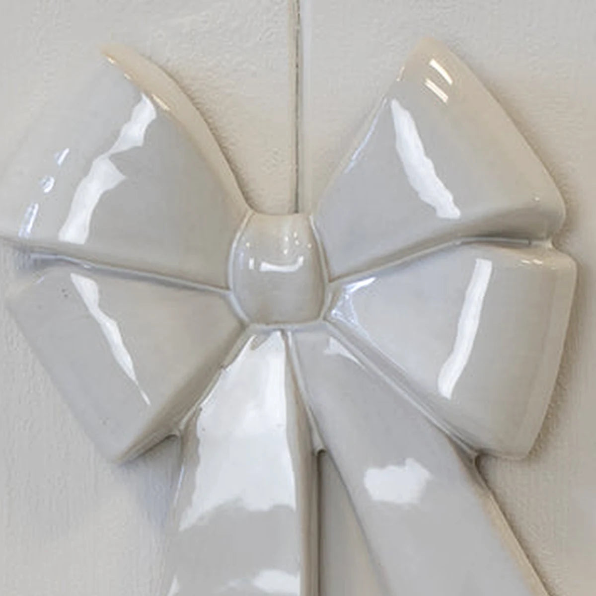 Close-up of glossy white double bow ceramic knot and raised folded loop details