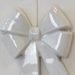 Close-up of glossy white double bow ceramic knot and raised folded loop details
