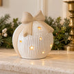 White ribbed ceramic light-up bauble styled with Christmas greenery on a pale mantel