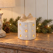 Cream ceramic LED present glowing on an oak console in a light Christmas hallway.