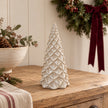Ivory pinecone style Christmas tree on an oak console in a festive country hallway